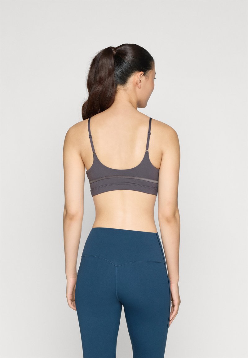 Grijze sportbeha met verstelbare bandjes en een naadloos ontwerp, gecombineerd met hooggesneden teal legging met zijaccentnaden.