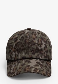 Gorra de béisbol con patrón de camuflaje hecha de tela; presenta un logo bordado en marrón en la parte frontal. Visera curvada y correa trasera ajustable.