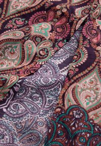 Material de mătase multicolor cu modele ornamentale paisley în nuanțe de violet, turcoaz, roz și auriu, cu detalii și textură intricate.