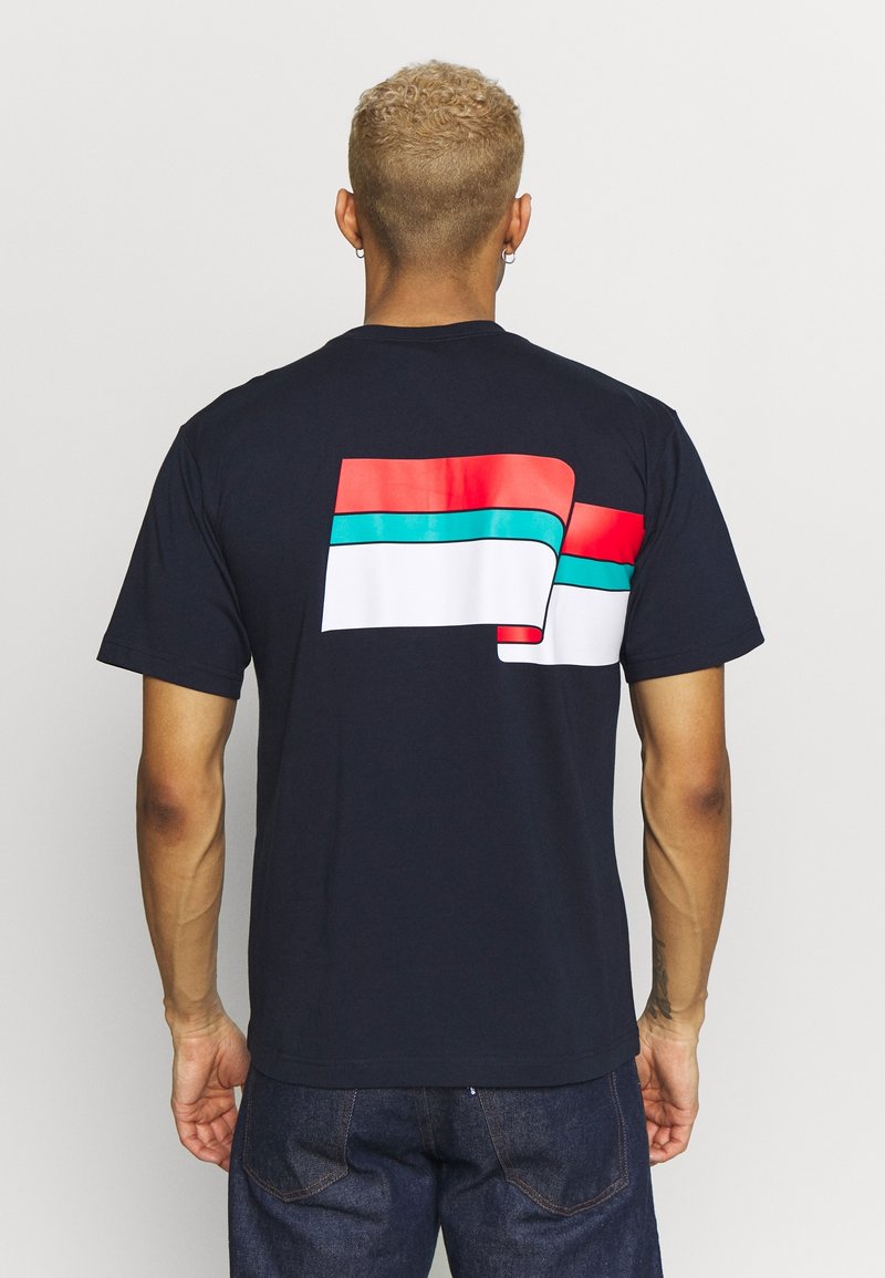 Mörkblå t-shirt med en djärv, flerfärgad grafik på baksidan; har röda, vita och akvamarin vågräta ränder. Kortsleeved.