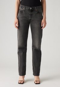Zwarte straight-leg jeans in donker vervaagd denim, met vijf zakken, koperen hardware en een tailleband met riemlussen.