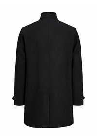 Melna vilnas mētelis ar augstu apkakli, garām piedurknēm un taisnu piegriezumu. Iezīmē minimālistisku dizainu un bez redzamiem metāla elementiem vai akcentiem.