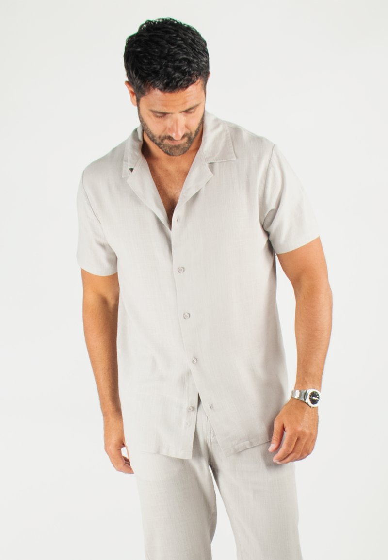 Chemise à manches courtes, gris clair, en tissu texturé. Dotée d'un col à revers et de subtils accents de boutons.