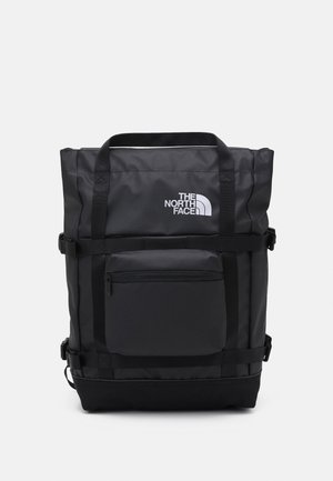 Schwarzer rechteckiger Rucksack von The North Face mit oberen Griffen, einer vorderen Reißverschlusstasche und verstellbaren Seitenträgern vor hellem Hintergrund.