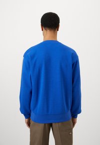 Blå hettegenser med rund hals, lange ermer, ribbestrikkede mansjetter og hem, med en teksturert overflate og en rett skjær.