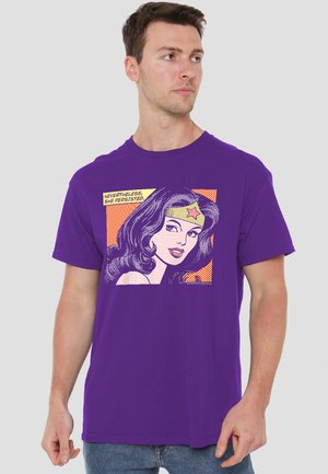 Man wearing purple shirt with comic-style Wonder Woman portrait and text "Nevertheless, she persisted" looking to the side.