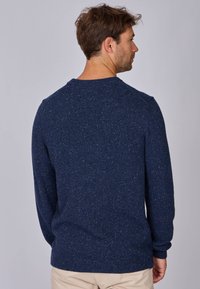 Pull en tricot bleu marine avec une finition texturée, doté de manches longues et d'un col rond. Des fils subtils ajoutent de l'intérêt visuel.