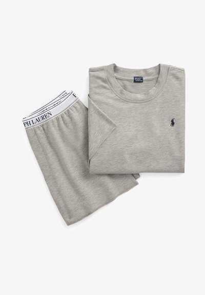 Hallikas puuvillane T-särk ja lühikesed püksid, millel on ümmargune kaelus, rullitud varrukad ja tumesinine logo T-särgil; vöökoht sisaldab kaubamärgi nime.