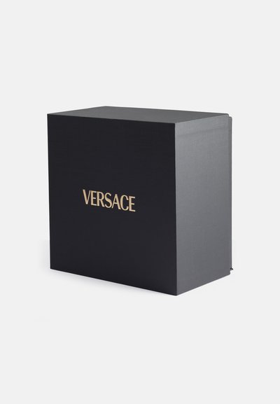 Scatola nera texturizzata con una finitura matte liscia. Logo dorato "VERSACE" sul fronte, con bordi netti e forma rettangolare.