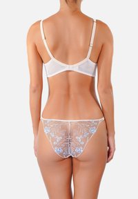 Ensemble de lingerie comprenant un soutien-gorge blanc à bretelles réglables et un string transparent orné de broderies florales bleues et d'une finition texturée.