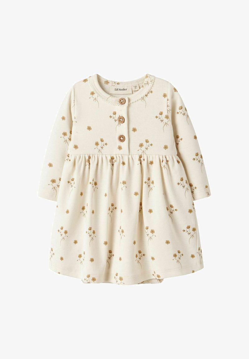 Kremna otroška obleka z dolgimi rokavi z majhnim rjavim cvetličnim potiskom, tremi lesenimi gumbi na prsih in nabranim krilom.