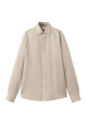Chemise beige à manches longues avec col pointu, sept boutons sur le devant et poignets boutonnés, présentée à plat sur un fond blanc.