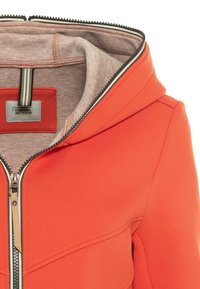 Orangenes Zip-Hoodie mit beigem Innenfutter und gestreiftem Reißverschlussdetail, ausgestattet mit einem Camel Active-Label im Kragen.
