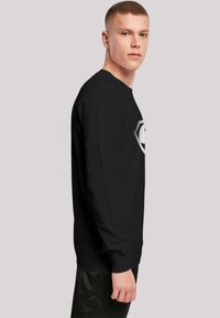 Black long-sleeve sweatshirt with a round neckline. Features a large graphic design on the front, smooth texture, and ribbed cuffs.