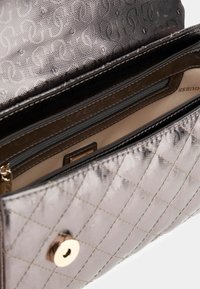 Metalen grijze portefeuille met een quiltpatroon, gouden hardware, één ritsvak en een gladde binnenvoering.