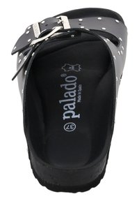 Sandali neri realizzati in materiale sintetico, con fibbia metallica, dettagli borchiati e fondo sagomato con logo. Design a suola piatta.