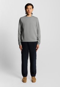 Grå sweatshirt i bomullsblandning, rund hals, långa ärmar. Matchas med marinblå byxor och bruna mocka loafers. Enkla och funktionella design.