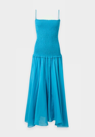 Robe bleue sans manches avec corsage ajusté smocké et jupe longue fluide sur un fond clair uni.