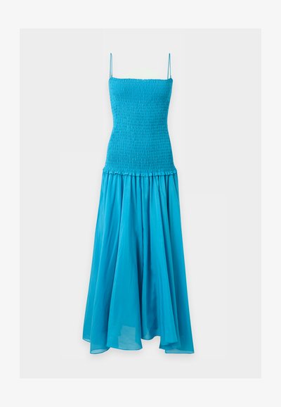Robe bleue sans manches avec corsage ajusté smocké et jupe longue fluide sur un fond clair uni.