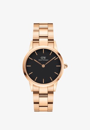Montre en or rose avec un boîtier rond, cadran noir et marqueurs minimalistes. Présente un bracelet en métal brillant avec une finition polie.