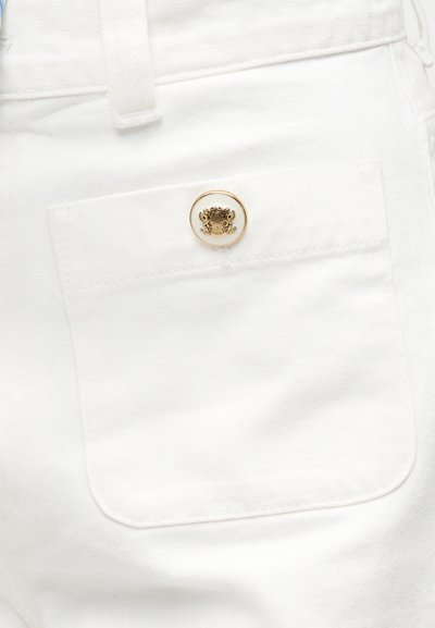 Λευκή τσέπη από τζιν με ένα μόνο λευκό και χρυσό κουμπί με ανάγλυφο σχέδιο θυρεού.
