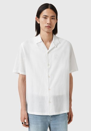 Camicia bianca a maniche corte realizzata in tessuto testurizzato, con chiusura a bottoni sul davanti, colletto a scollatura e un sottile ricamo sul petto.