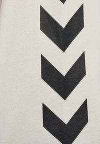 Zwart chevronpatroon op een crèmekleurige stofachtergrond, met getextureerde lijnen en een gebreide uitstraling, die een gedurfde geometrische voorstelling toont.