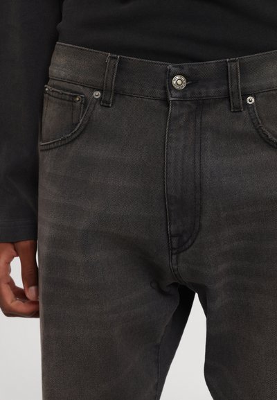 Crne traperice od denima s izblijedjelim završetkom, s pet džepova, kopčanjem na gumb i kontrastnim šavovima. Glatka tekstura i kroj koji prati tijelo.