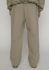 Beige Jogginghose mit lockerem Schnitt, aus weichem Stoff, mit Kordelzug in der Taille, Seitentaschen und leicht zulaufenden Bündchen.