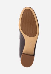 Semelle en cuir marron avec une surface texturée, forme arrondie et un talon en caoutchouc beige contrastant. Présente une marque au niveau du talon.