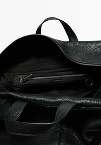 Black leather bag with a textured surface, zippered closure, and a soft fabric lining. Includes an internal zippered pocket.