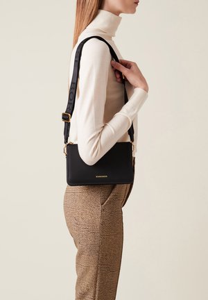 Sac bandoulière noir en cuir lisse, doté d'une sangle texturée avec logo et accessoires en métal doré. Design rectangulaire simple.
