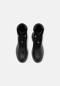 Black leather ankle boots with round toes, gold hardware accents, lace-up front, and padded collars for comfort. Smooth texture.