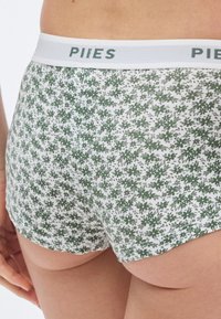Medvilniniai šortai boxer stiliaus, balti su žaliu gėlių raštu, elastine juosmens juosta su „PIIES“ logotipu. Minkšta tekstūra, prigludęs dizainas ir vidutinio aukščio kirpimas.