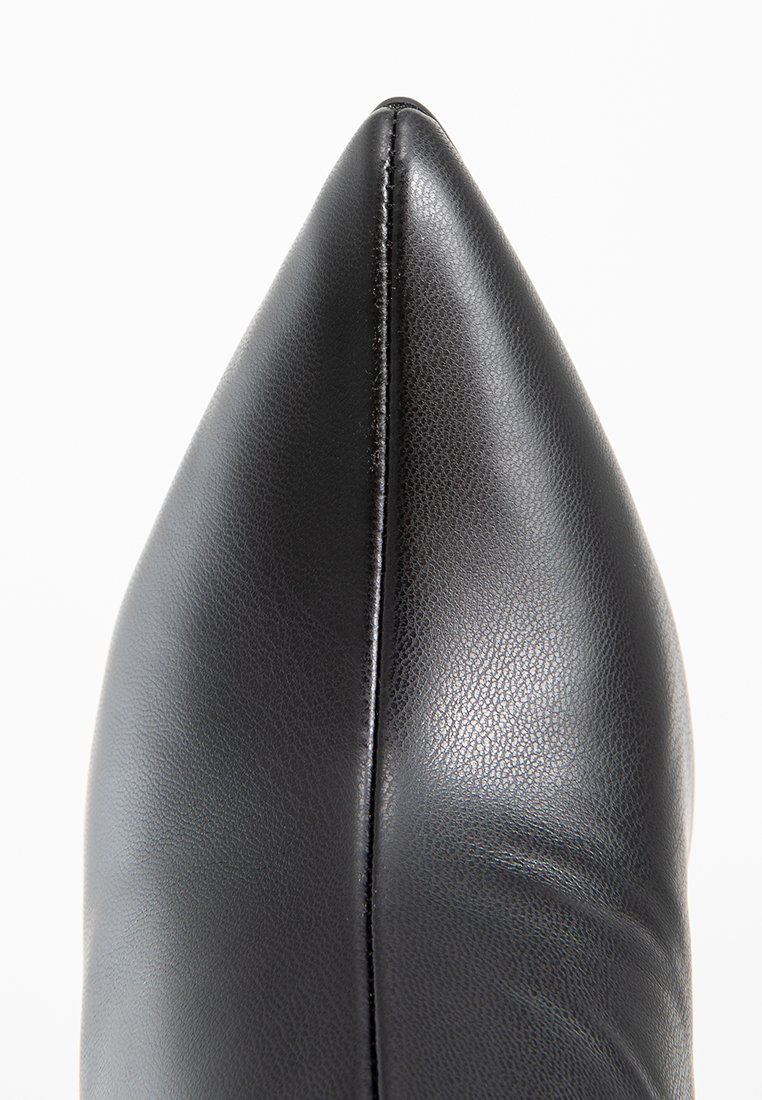 Czarne skórzane buty na obcasie z ostro zakończonym noskiem, charakteryzujące się gładką teksturą i wyraźnym szwem wzdłuż cholewki, elegancko zwężające się do ostrego czubka.