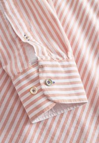 Tessuto a righe di colore rosa chiaro e bianco con polsini abbottonati. Presenta bordi dei polsini arrotondati e bottoni decorativi con motivi floreali.