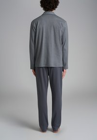 Giacca grigia a righe con vestibilità comoda, abbinata a pantaloni grigi scuri in tinta unita. Tessuto morbido con una superficie liscia, design minimalista.