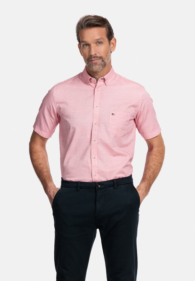 Korte mouwen, button-down shirt in lichtroze stof met een subtiele textuur. Beschikt over een borstzak aan de linkerkant en een getailleerd ontwerp. Draagt met donkere broek.