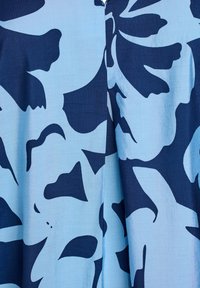 Blauter Stoff mit einem großen Blumenmuster in dunklem Marineblau, mit glatter Textur und einer naht, die vertikal in der Mitte verläuft.