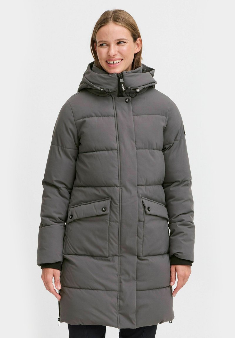 Grå pufferjakke med hette, quiltet design, frontglidelås og knappelukking. Har to sidelommer med klaff.