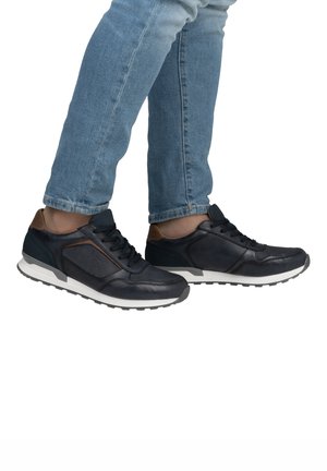 Zapatillas de cuero azul marino con paneles de malla, detalles en marrón, agujetas redondas y una suela de goma blanca. Acabado texturizado con un diseño aerodinámico.