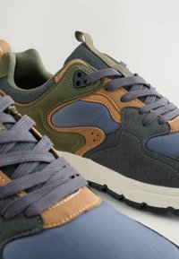 Wielokolorowe sneakersy z mieszanką zielonych, niebieskich, brązowych i szarych materiałów. Teksturowana nakładka z tkaniny, wyściełany kołnierz oraz gumowa podeszwa.