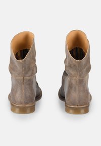 Botas de tobillo de cuero marrón con un acabado ligeramente desgastado, superficie texturizada, punteras redondeadas y un tacón bajo apilado.