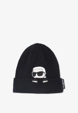Beanie lavorato a maglia nero con risvolto. Presenta un personaggio ricamato bianco che indossa occhiali da sole e tre punti bianchi sul risvolto.