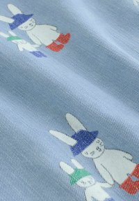 Bombažna tkanina s svetlo modrim ozadjem in igrivimi ilustracijami zajcev. Zajci nosijo rdeče škornje in pisane klobuke, tekstura je gladka.