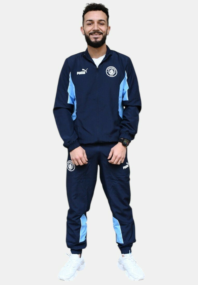 Chándal navy con acentos en azul claro, que cuenta con una chaqueta con cremallera y puños elásticos. Logotipo en el pecho y los pantalones. Deportivas blancas completan el conjunto.