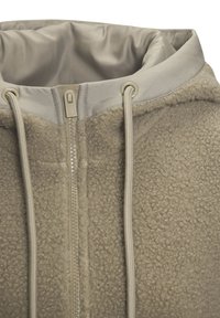 Fleecejacke in Beige mit glattem Innenfutter. Verfügt über einen vorderen Reißverschluss, Kordelzüge und eine strukturierte Außenfabric für Wärme.