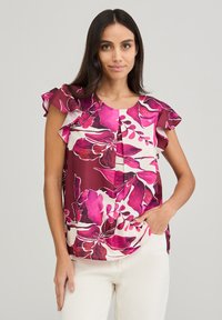 Blusa floreale bordeaux con fiori rosa e crema. Presenta maniche a volant e scollatura rotonda. Realizzata in tessuto leggero.