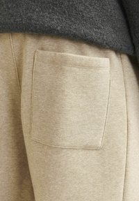 Beige sweatpants lavet af blødt stof, med en rektangulær baglomme med syninger. Casual design med en behagelig pasform.