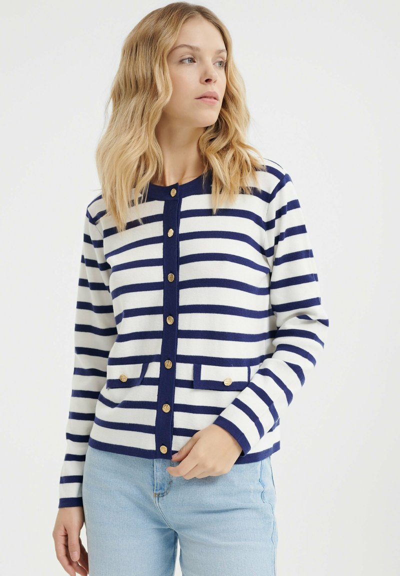 Cardigan a righe navy e bianche realizzato in tessuto a maglia, con scollo rotondo, bottoni dorati e due tasche frontali.
